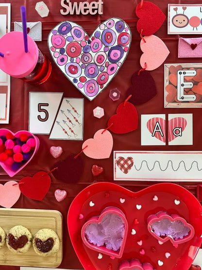 Valentine's Day-themed items including a heart-shaped cookie, pink drink with a straw, and decorative hearts on a red background.