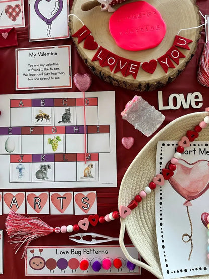 Valentine's Day-themed items including a cake, cards, and educational materials on a red background.